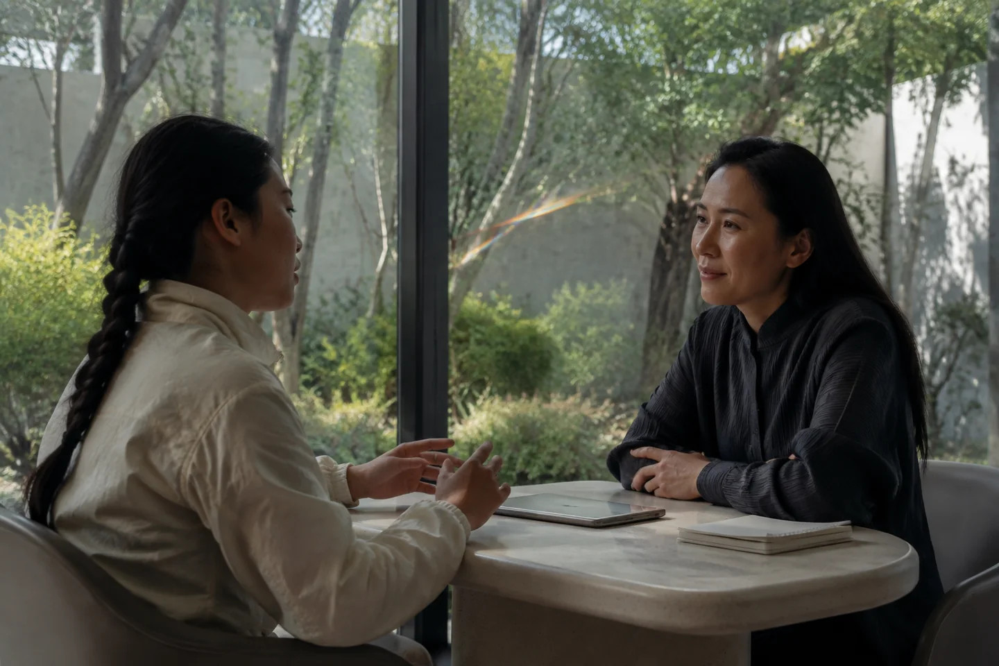 A practitioner listens to a client across a table in a bright room
