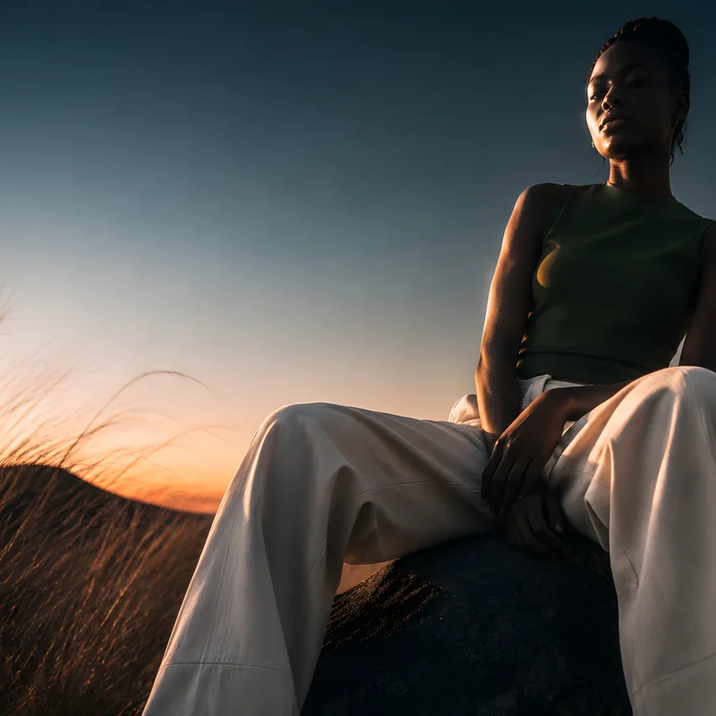 A woman resting on a rock at dusk
